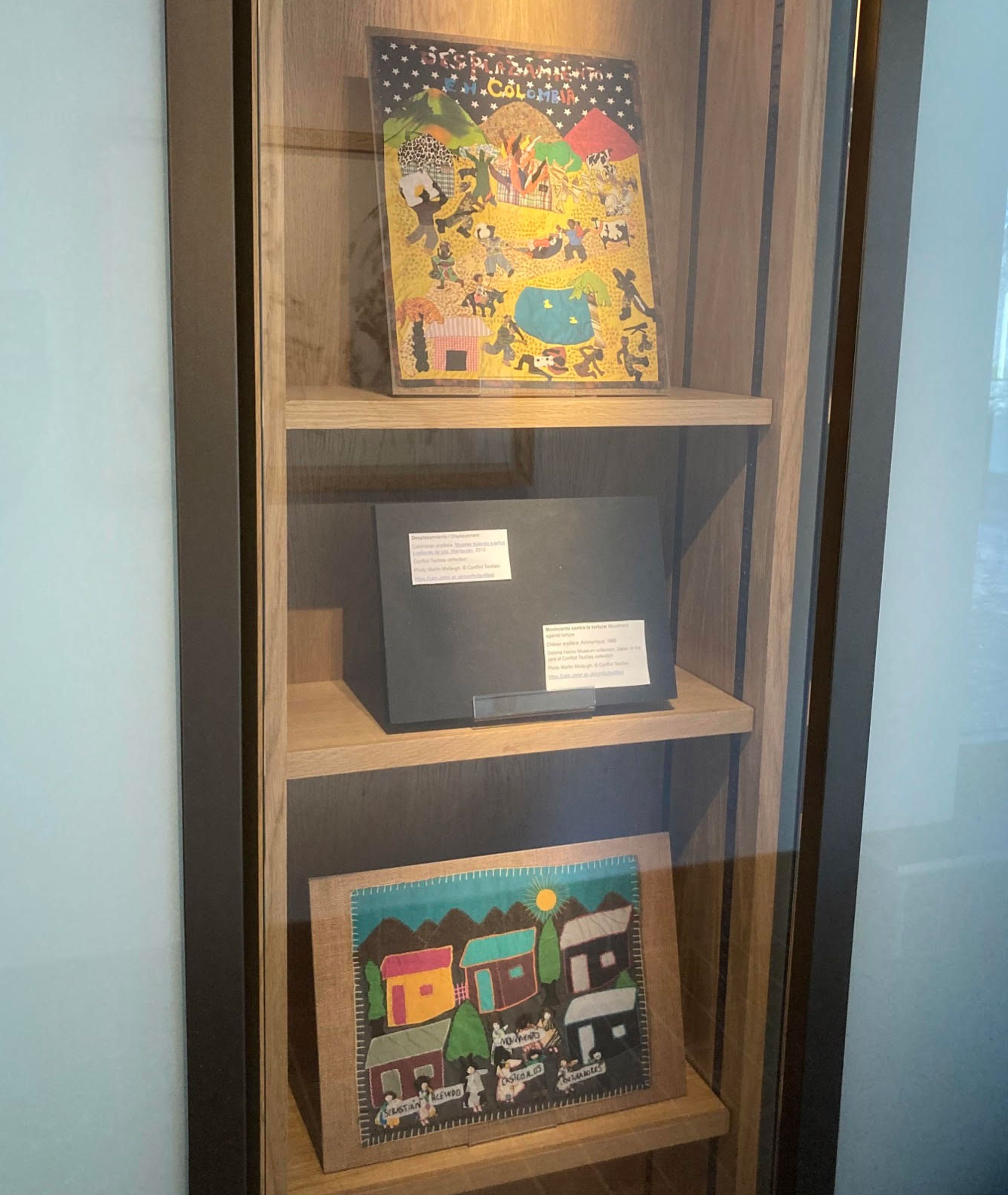 Images of two textiles 'Desplazamiento / Displacement' and 'Movimiento contra la tortura / Movement against torture', displayed in book cabinets at Wolfson College for the duration of the Oxford Human Rights Festival.  (Photo: Nicholas Marquez-Grant)
