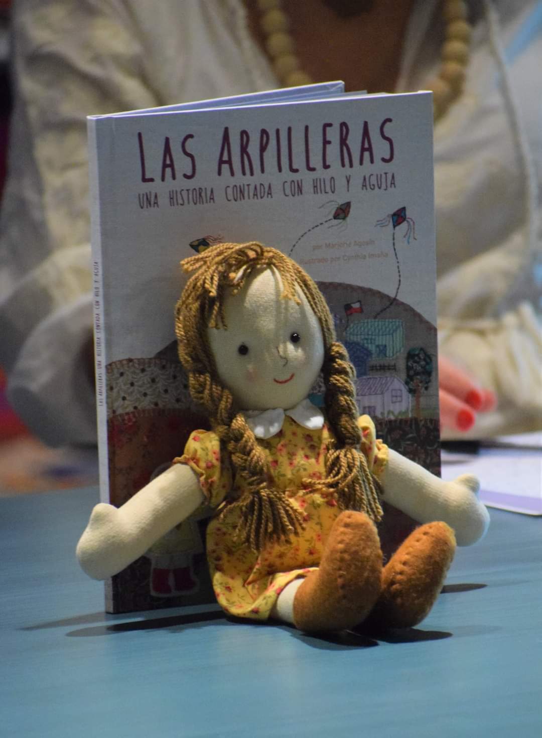 Doll made by Cynthia Imaña rests against the book 