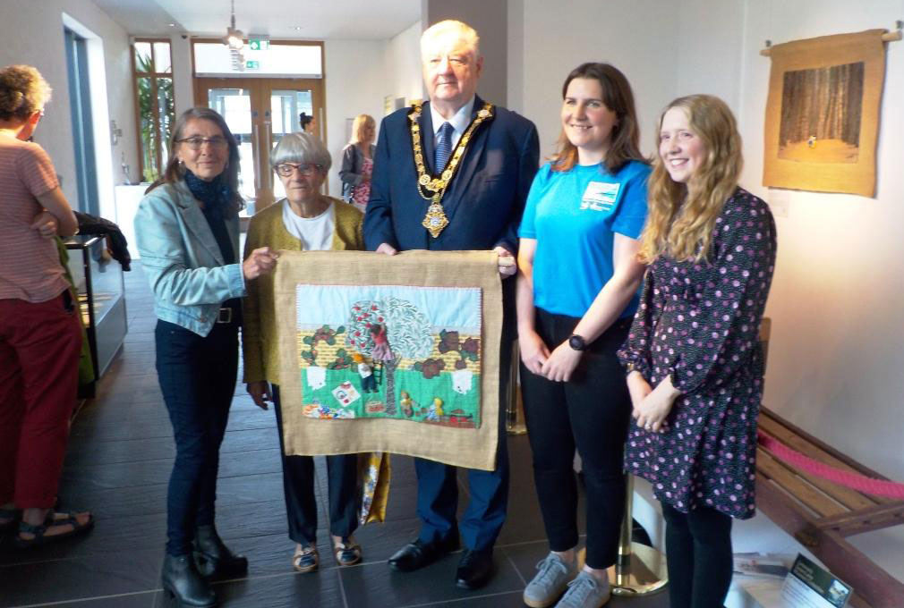 Pictured at the exhibition launch with the arpillera 'Life with and without Bees', L-R: Curator Roberta Bacic, textile artist Marlene Milner, Mayor Steven Callaghan, and from our partners, Grace McAlister and Jamie Austin.  (Photo: Clem McCartney)